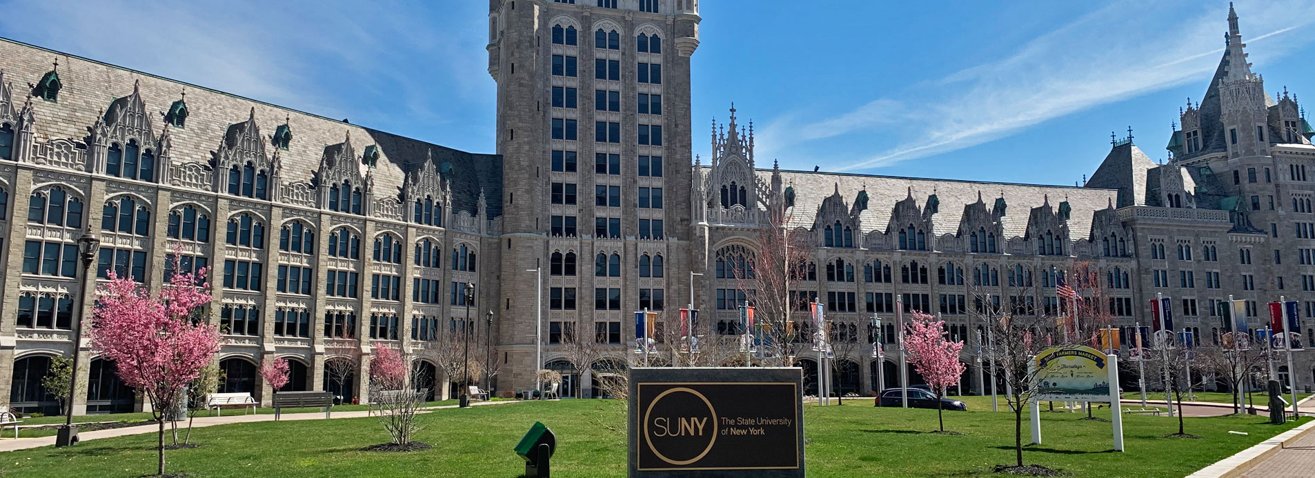 SUNY Plaza with sign in front in bright sunlight from April 2020.